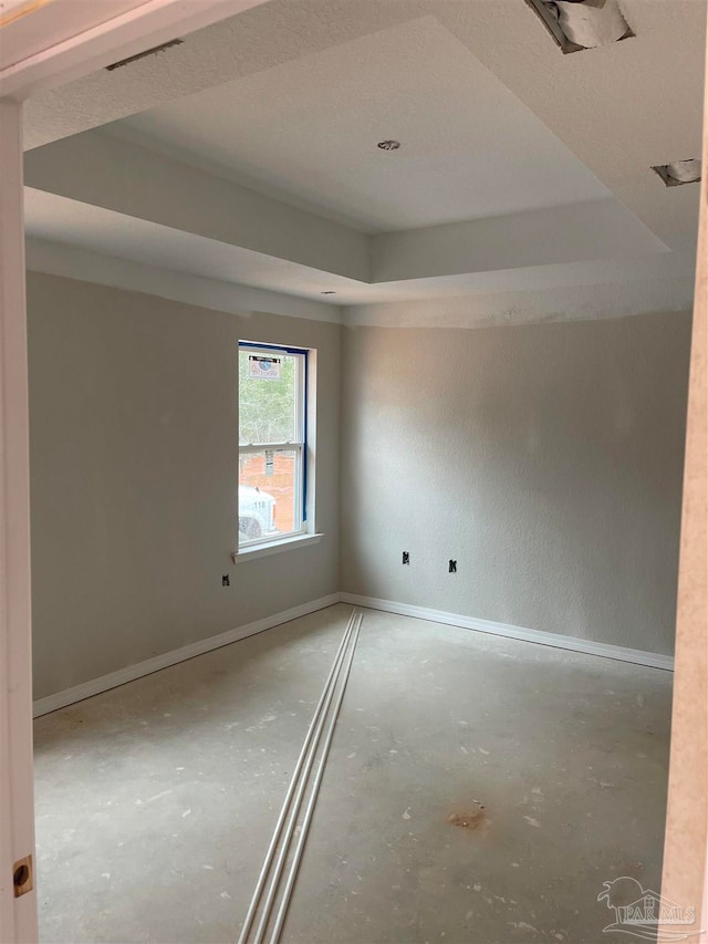 empty room with a raised ceiling and concrete flooring