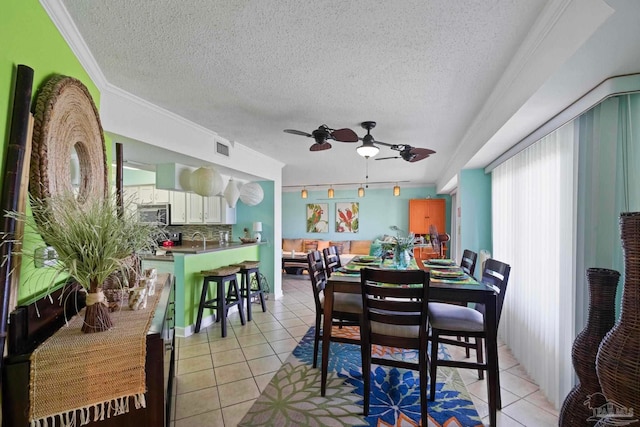 dining area featuring ceiling fan, a textured ceiling, crown molding, and light tile patterned flooring