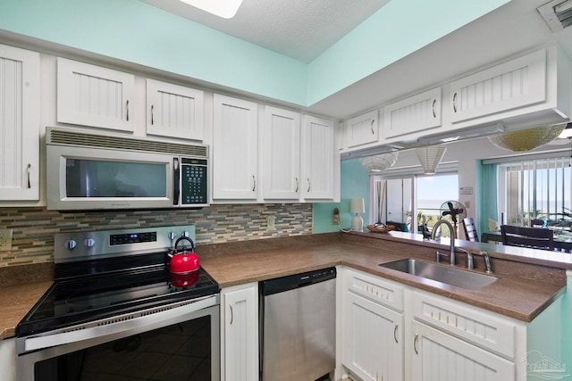 kitchen featuring sink, stainless steel appliances, decorative backsplash, and white cabinets