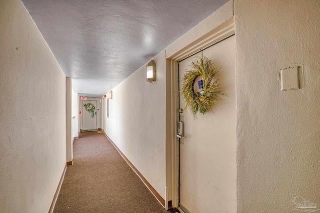 hall featuring carpet and a textured ceiling