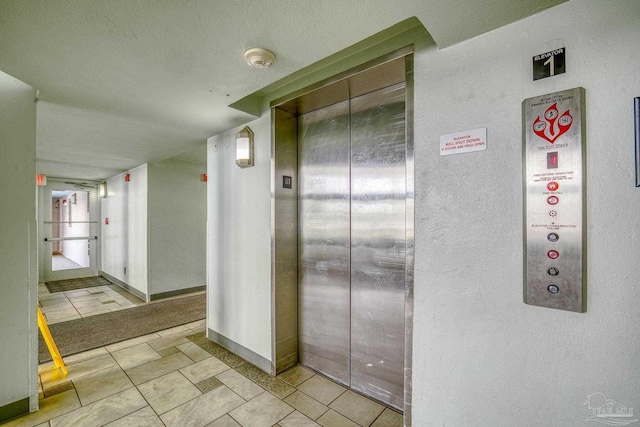 hall featuring light tile patterned floors, elevator, and baseboards