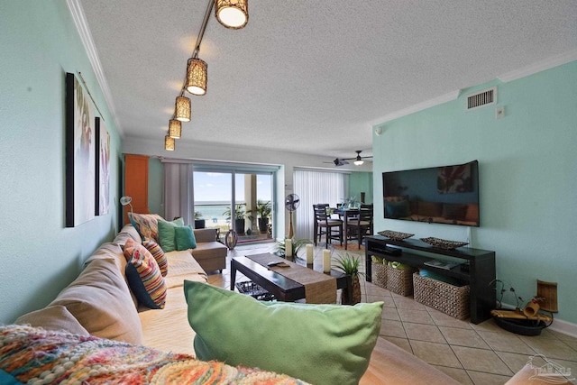 living area featuring ornamental molding, visible vents, a textured ceiling, and light tile patterned flooring