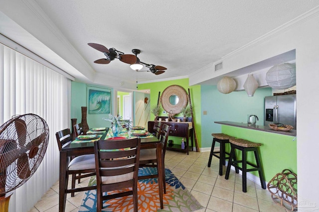 tiled dining room featuring ceiling fan, a textured ceiling, and crown molding