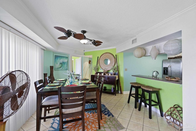 dining space with a textured ceiling, ceiling fan, ornamental molding, and light tile patterned flooring