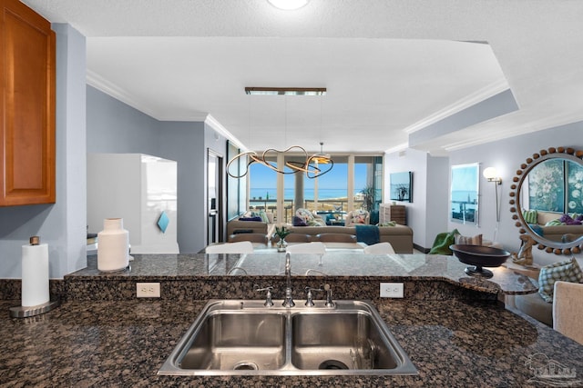 5 Portofino Dr Unit 703, Pensacola Beach, FL 32561 - kitchen featuring ornamental molding, open floor plan, brown cabinets, dark stone countertops, and a chandelier