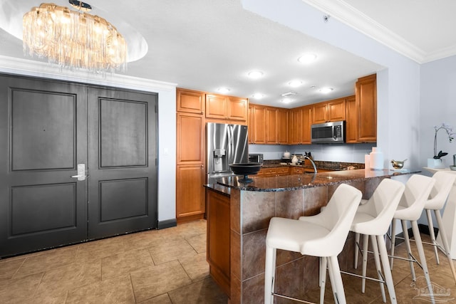 5 Portofino Dr Unit 703, Pensacola Beach, FL 32561 - kitchen with stainless steel appliances, crown molding, dark stone counters, brown cabinetry, and a peninsula