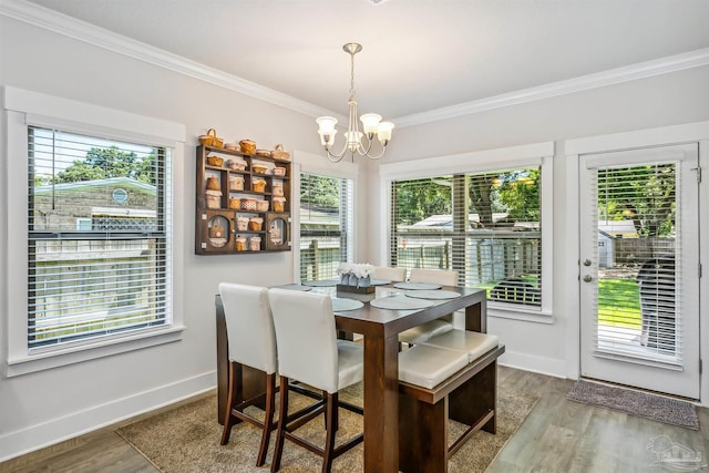 dining space with hardwood / wood-style flooring, ornamental molding, a chandelier, and plenty of natural light