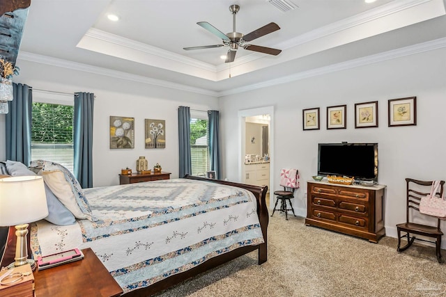 carpeted bedroom featuring a raised ceiling, ceiling fan, crown molding, and connected bathroom