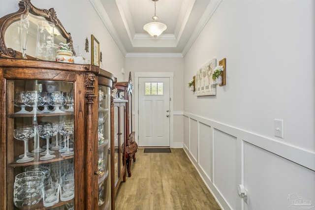 doorway to outside featuring a tray ceiling, crown molding, and hardwood / wood-style floors