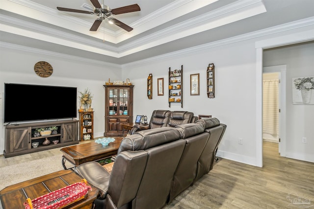 living room with a raised ceiling, ceiling fan, and ornamental molding