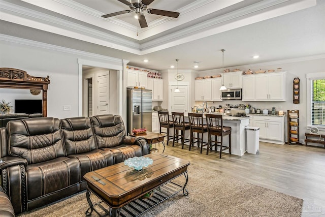 living room with ceiling fan, light wood-type flooring, and ornamental molding