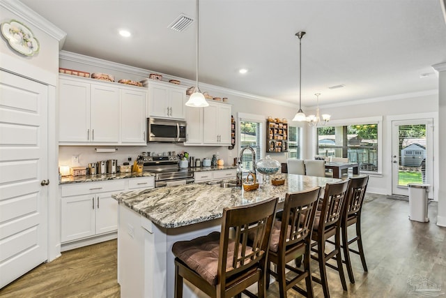 kitchen with white cabinets, a kitchen bar, a kitchen island with sink, and appliances with stainless steel finishes