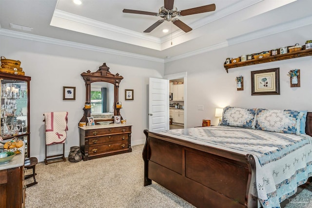 bedroom with ensuite bathroom, a tray ceiling, ornamental molding, ceiling fan, and light carpet