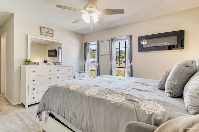 bedroom with ceiling fan, light colored carpet, and a textured ceiling