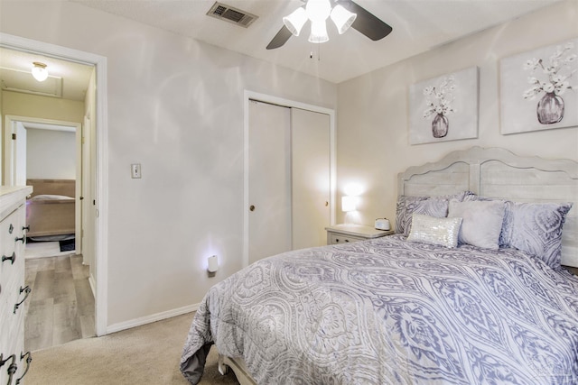 bedroom with baseboards, visible vents, ceiling fan, a closet, and light carpet