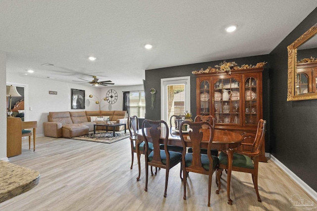 dining space with ceiling fan, a textured ceiling, and light wood-type flooring