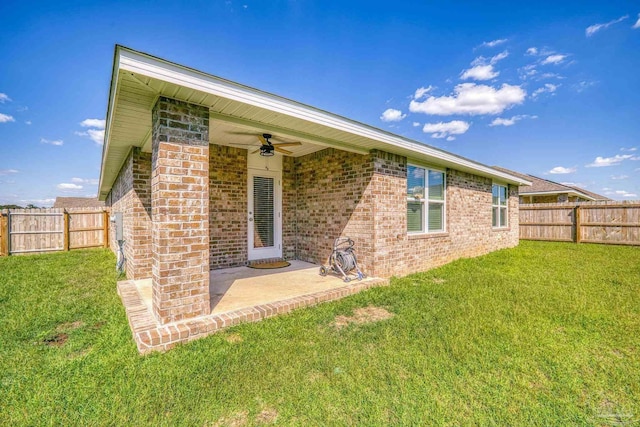 rear view of property featuring a yard, a patio area, and ceiling fan