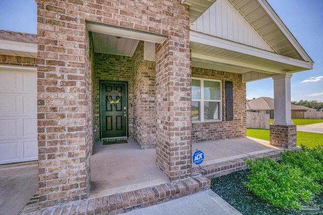 view of exterior entry featuring a garage and covered porch