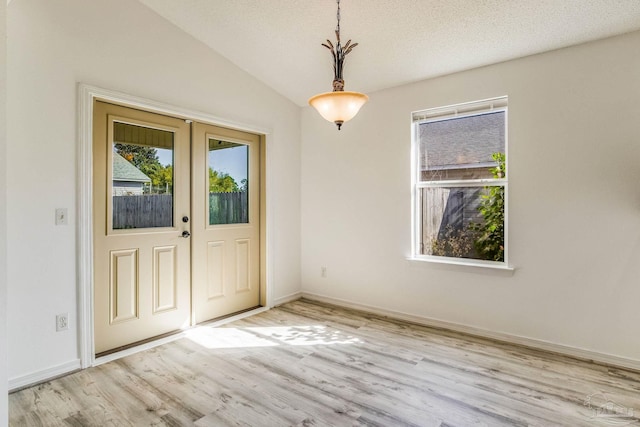 entrance foyer with a textured ceiling, light hardwood / wood-style flooring, lofted ceiling, and french doors