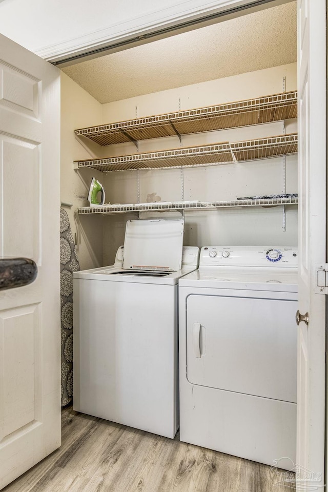 laundry room featuring washer and dryer and light hardwood / wood-style flooring