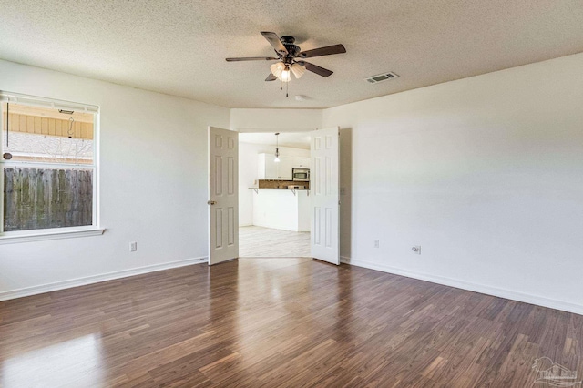 empty room featuring ceiling fan, a textured ceiling, and dark hardwood / wood-style floors