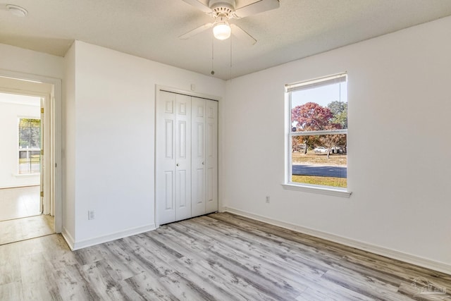 unfurnished bedroom featuring ceiling fan, a closet, and light wood-type flooring