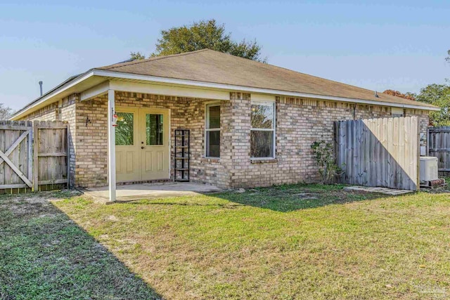 rear view of house featuring central AC unit, a yard, and a patio