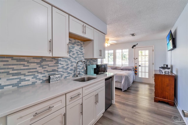 kitchen with dishwasher, light countertops, a sink, and white cabinets