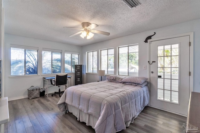 bedroom featuring a textured ceiling, wood finished floors, visible vents, and a ceiling fan