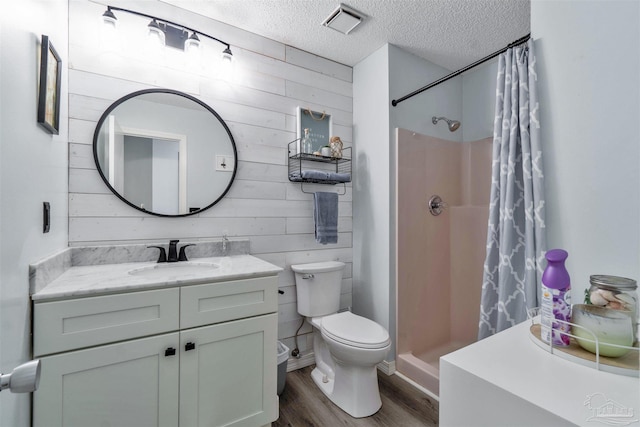 full bath with a stall shower, wooden walls, toilet, wood finished floors, and a textured ceiling