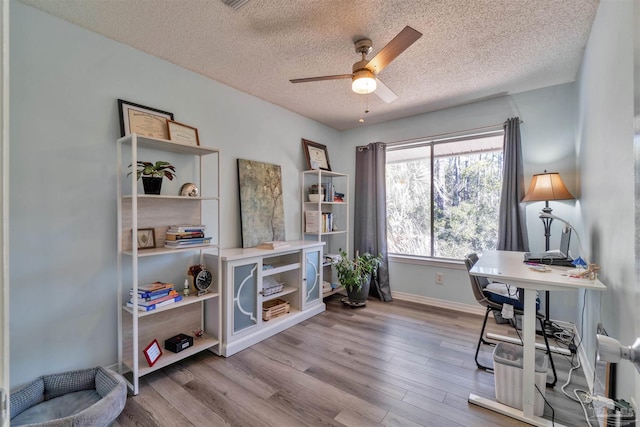 office space featuring a ceiling fan, a textured ceiling, baseboards, and wood finished floors