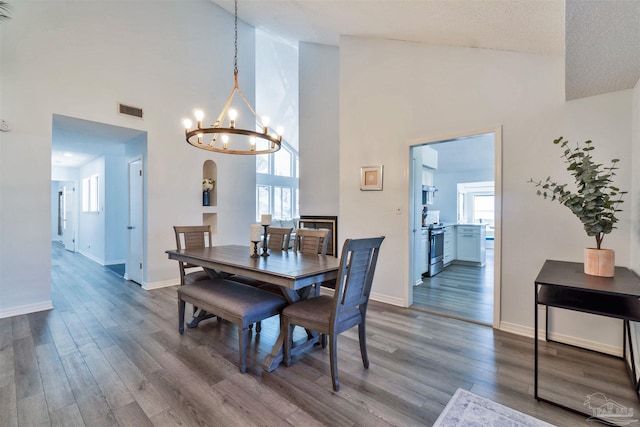 dining space with baseboards, wood finished floors, visible vents, and a notable chandelier