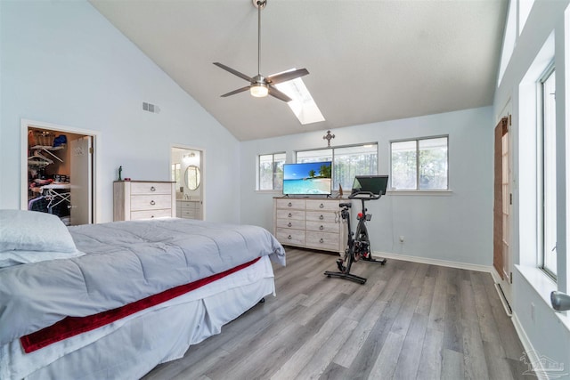 bedroom featuring a skylight, visible vents, wood finished floors, high vaulted ceiling, and baseboards