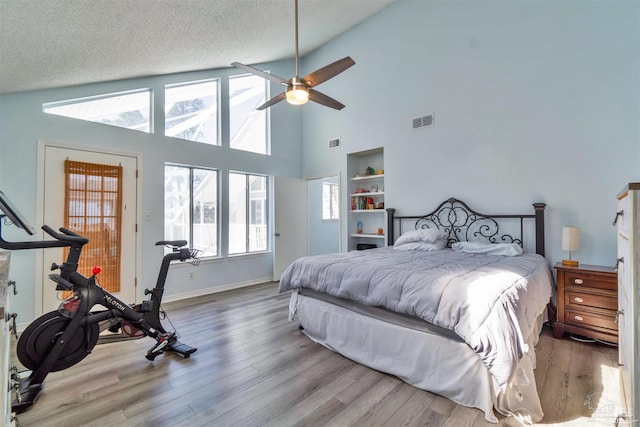 bedroom with a textured ceiling, vaulted ceiling, wood finished floors, and visible vents