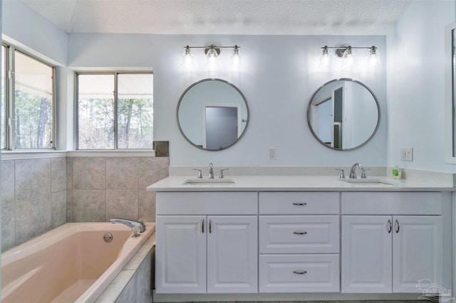 bathroom with a garden tub, a sink, a textured ceiling, and double vanity