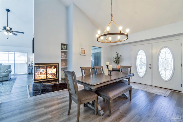 dining area with wood finished floors, a multi sided fireplace, built in shelves, and a healthy amount of sunlight