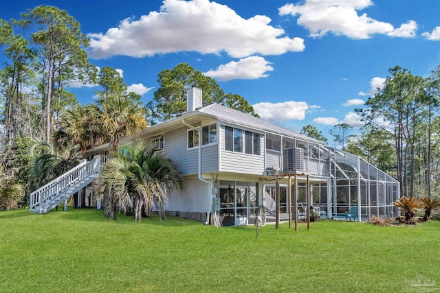 back of house featuring glass enclosure, stairway, and a lawn