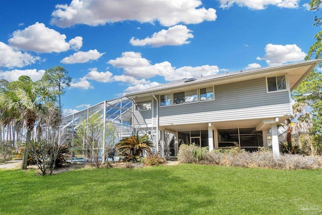 back of property with glass enclosure and a yard