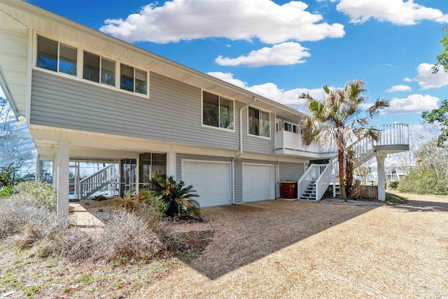 back of house featuring concrete driveway, an attached garage, and stairs