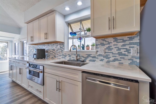 kitchen featuring stainless steel appliances, light countertops, light wood-style flooring, a sink, and a textured ceiling