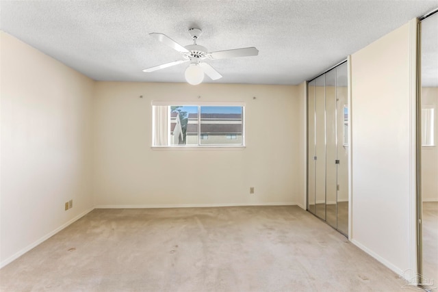 unfurnished bedroom featuring light carpet, a textured ceiling, and ceiling fan