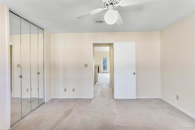 unfurnished bedroom with a closet, ceiling fan, a textured ceiling, and light colored carpet