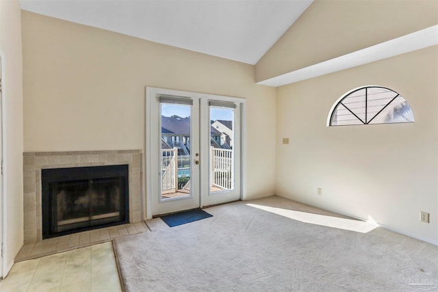 unfurnished living room with french doors, light colored carpet, a fireplace, and vaulted ceiling