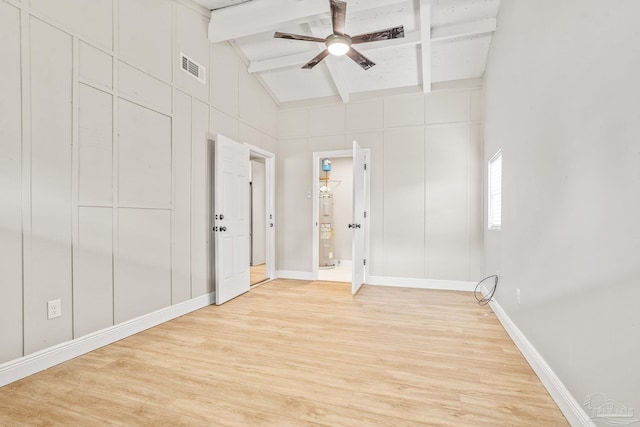 empty room with ceiling fan, beam ceiling, high vaulted ceiling, and light hardwood / wood-style flooring