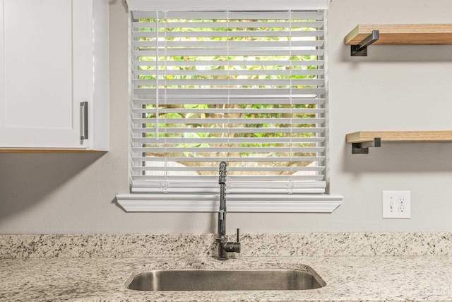 details with light stone countertops, sink, and white cabinets