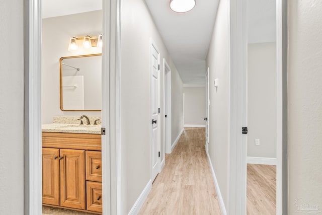 corridor featuring sink and light wood-type flooring