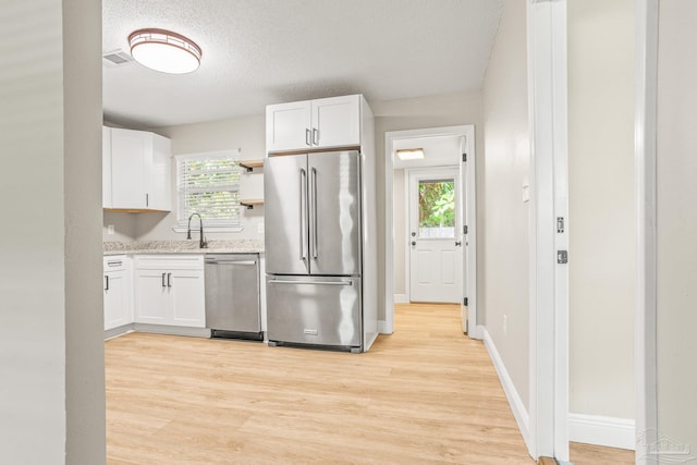 kitchen with white cabinetry, a healthy amount of sunlight, stainless steel appliances, and a textured ceiling