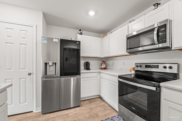 kitchen featuring white cabinetry, stainless steel appliances, and light wood-type flooring