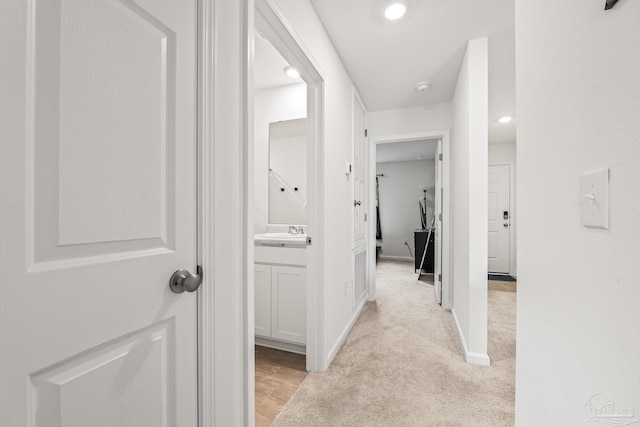 hallway featuring sink and light colored carpet