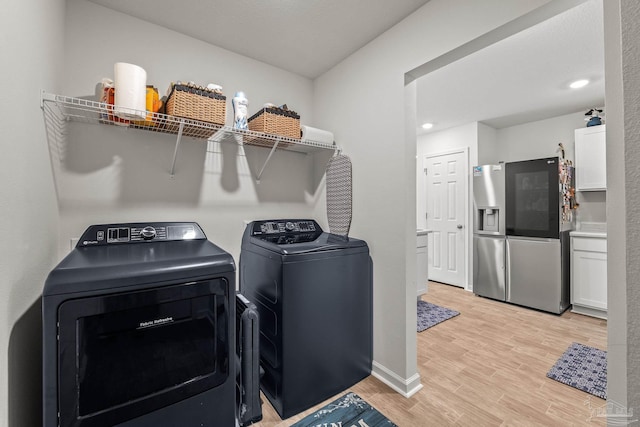 laundry area with washer and dryer and light hardwood / wood-style flooring